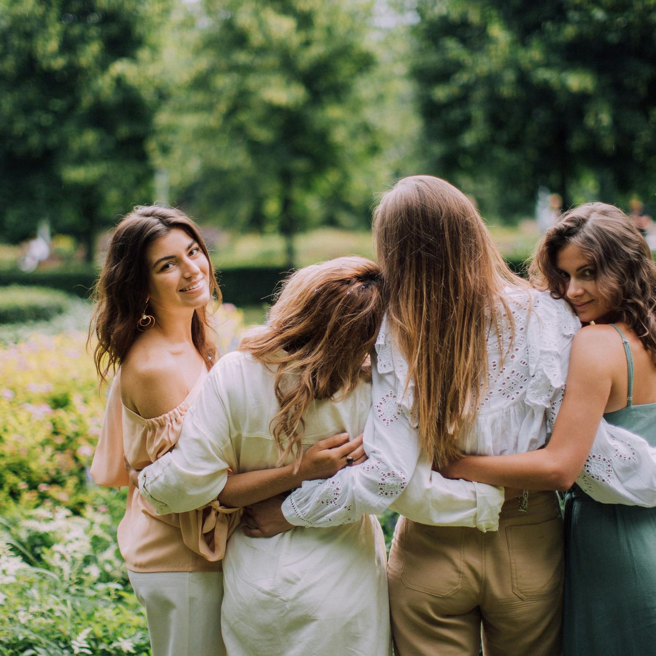 Handen warmen zich bij een vuurplaats met vlammen, in de buitenlucht. Op één arm is een blauwe vogel getatoeëerd.