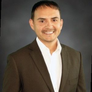 A man in a suit and white shirt is smiling for the camera.
