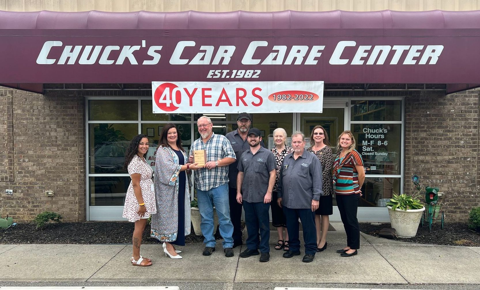 A small business owner is typing on a laptop while holding a cell phone.