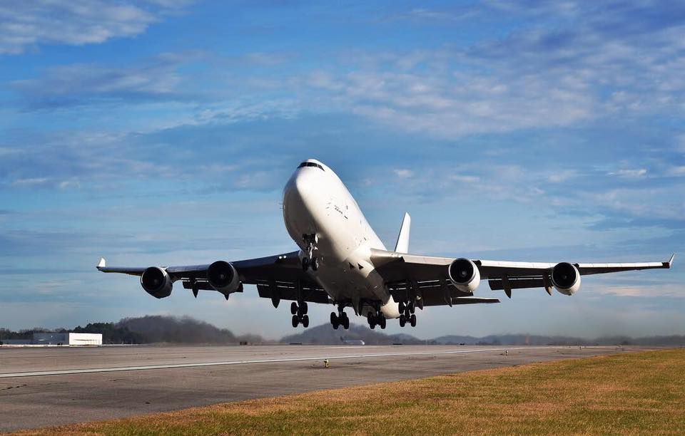 A large passenger jet is taking off from an airport runway at sunset.
