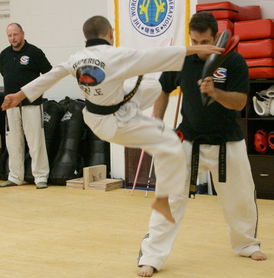 Two men grappling on a mat, one in blue, the other in black.