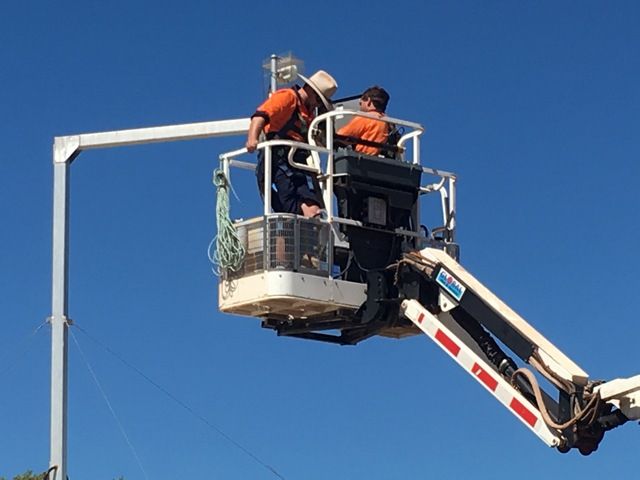 Two Men Are Working on a Light Pole on a Crane — Sape Industries in Garbutt, QLD