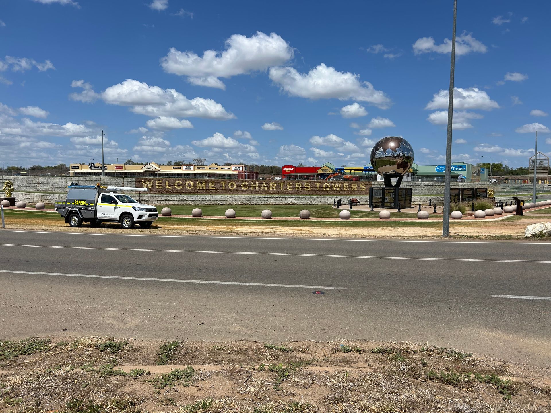 A white truck is parked on the side of the road in front of a welcome sign.
