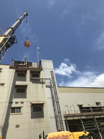 Crane is Lifting a Bucket From the Roof of a Building — Sape Industries in Garbutt, QLD