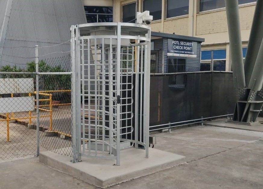 A security booth is behind a turnstile in front of a building