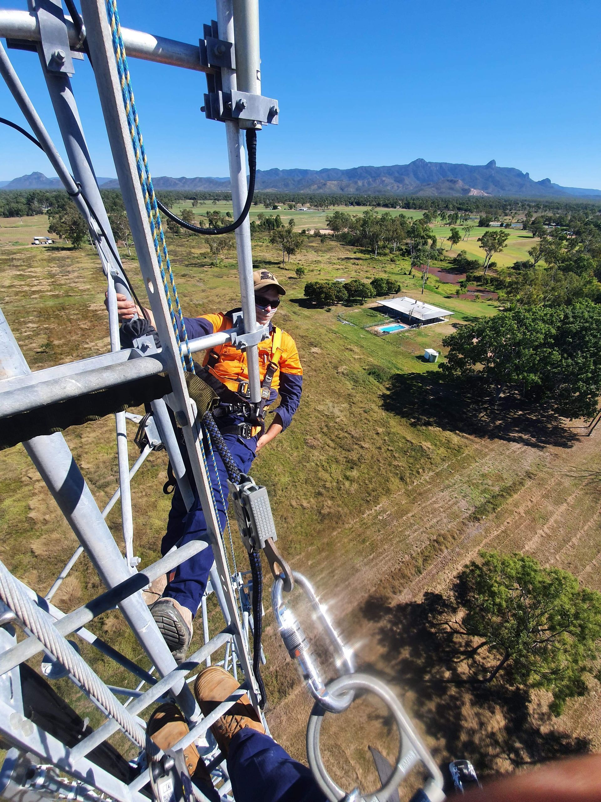 A man is working on a tower in a field.