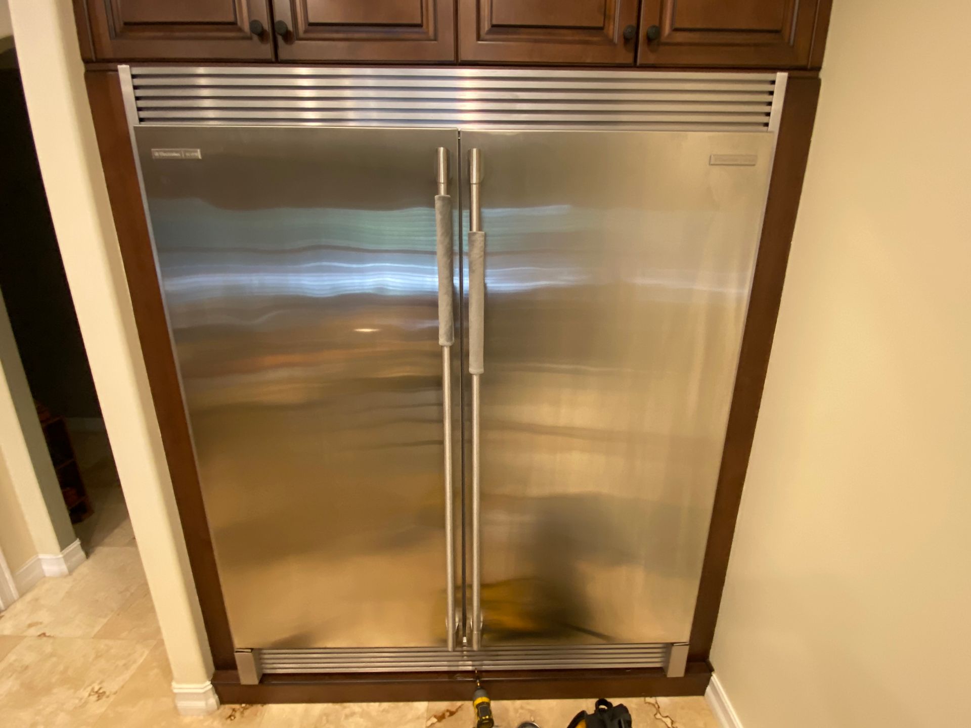 Stainless steel refrigerator built into dark wood cabinetry.