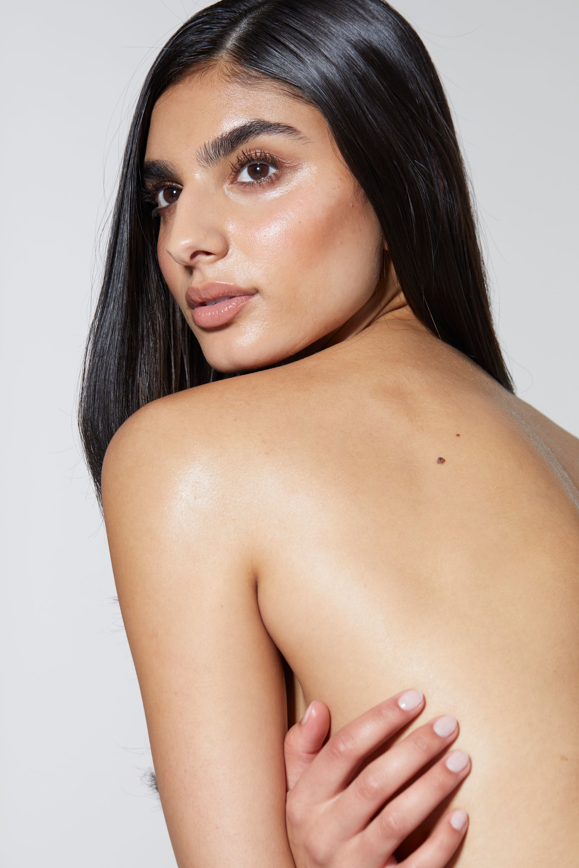 Eine Frau Oberkörper frei schaut über ihre Schulter in die Kamera.