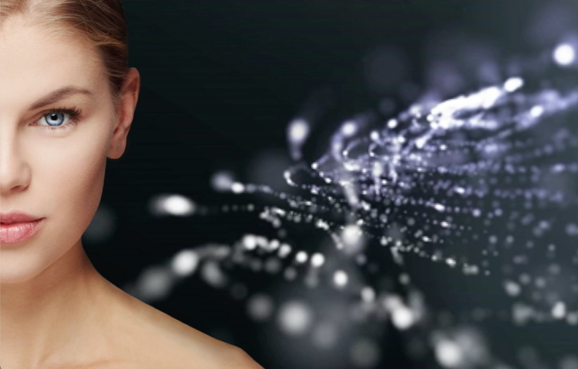 Eine Nahaufnahme des Gesichts einer Frau mit spritzendem Wasser im dunklen Hintergrund.