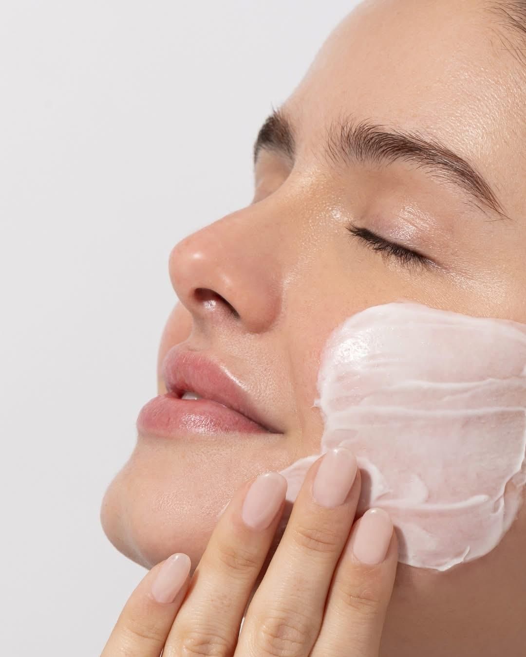 Eine Frau trägt eine Creme auf ihr Gesicht auf.