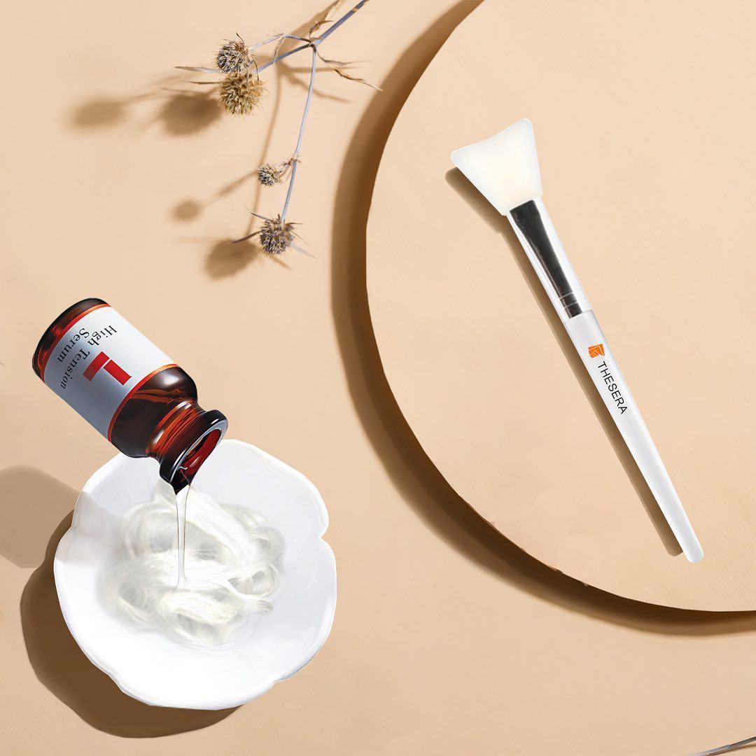 Kosmetikartikel: kleines Fläschen und Pinsel auf beigen Hintergrund