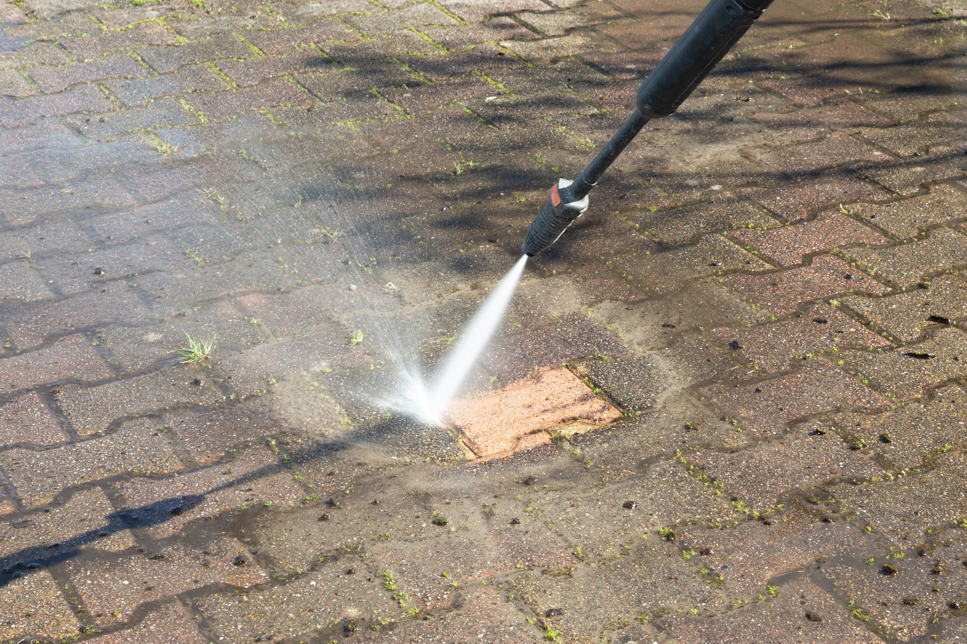 A man is spraying a green trash can with a spray bottle.