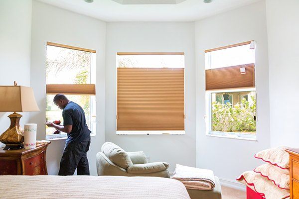 Man Installing Window Shades in Bedroom — Iowa City, IA — S&S Window Treatments