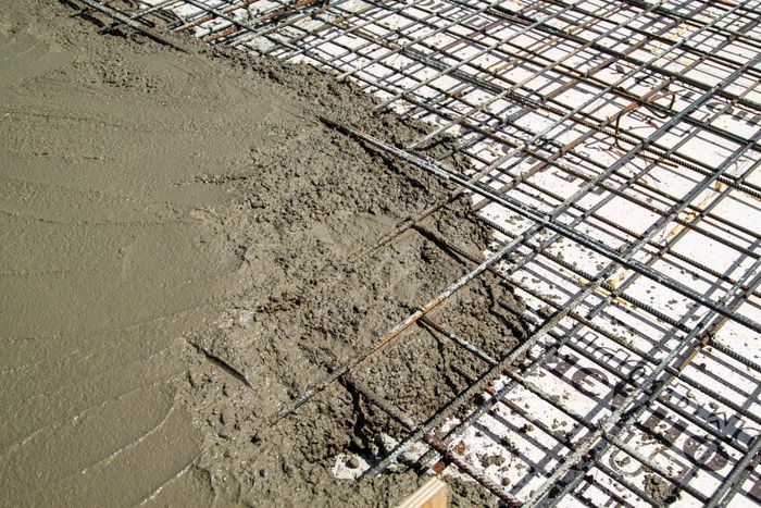 Fresh concrete being poured over a rebar grid.