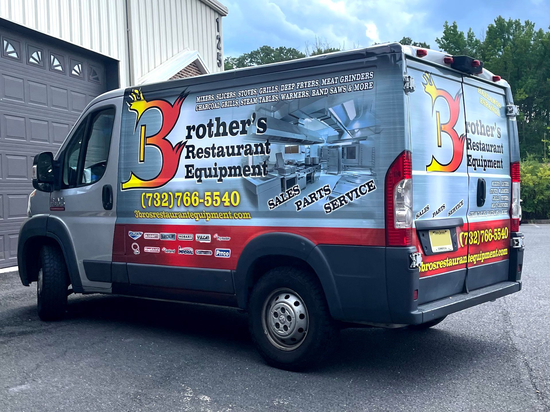 A rothers restaurant equipment van is parked in front of a garage.