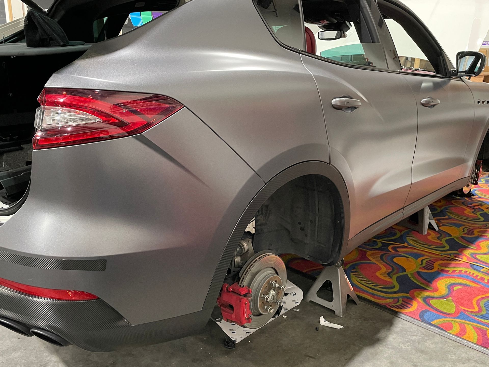 A car with a broken wheel is sitting on a stand.