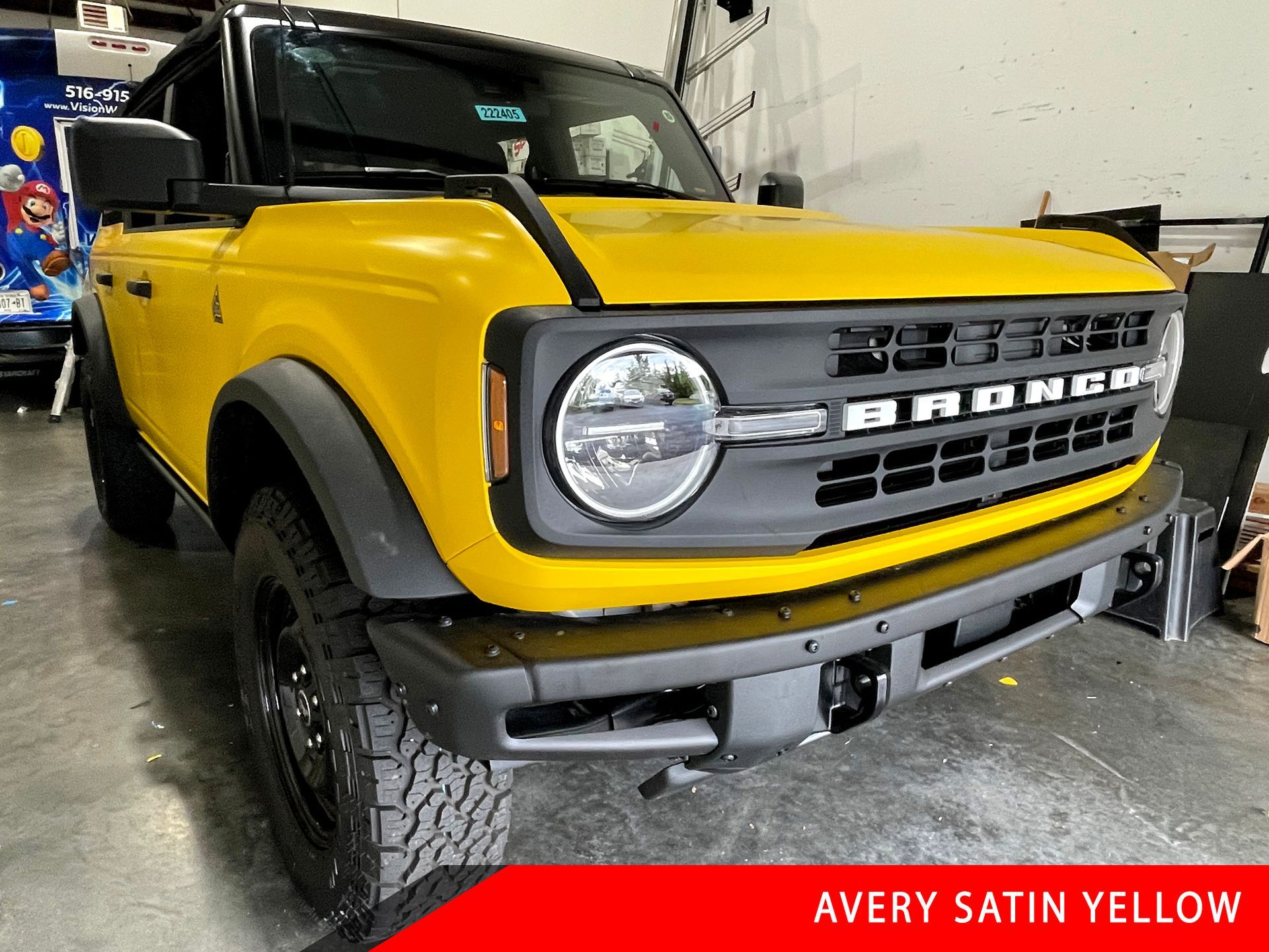 A yellow ford bronco is parked in a garage.