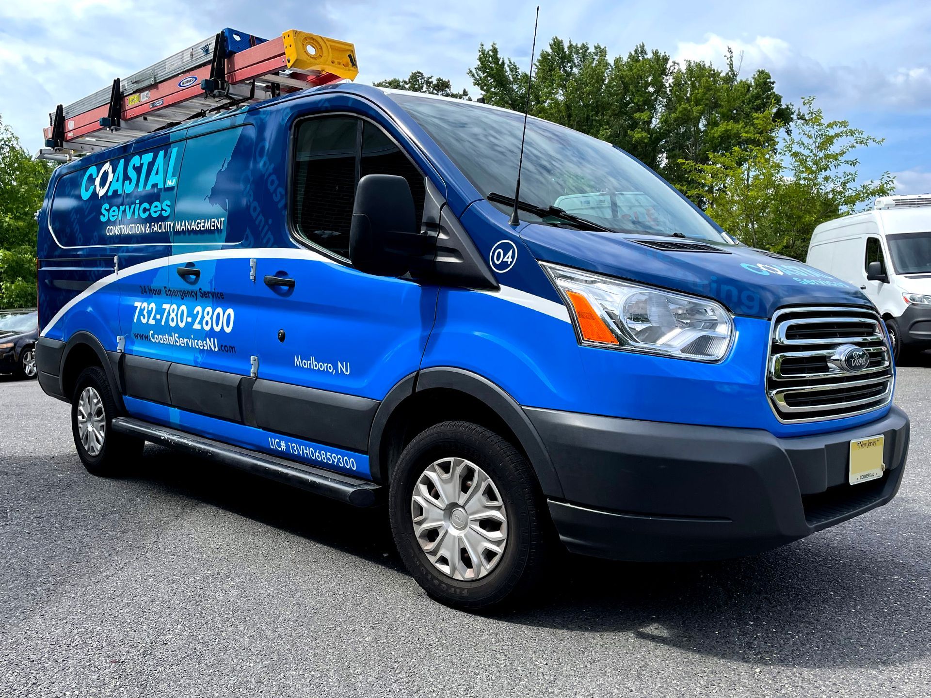 A blue coastal services van is parked in a parking lot.