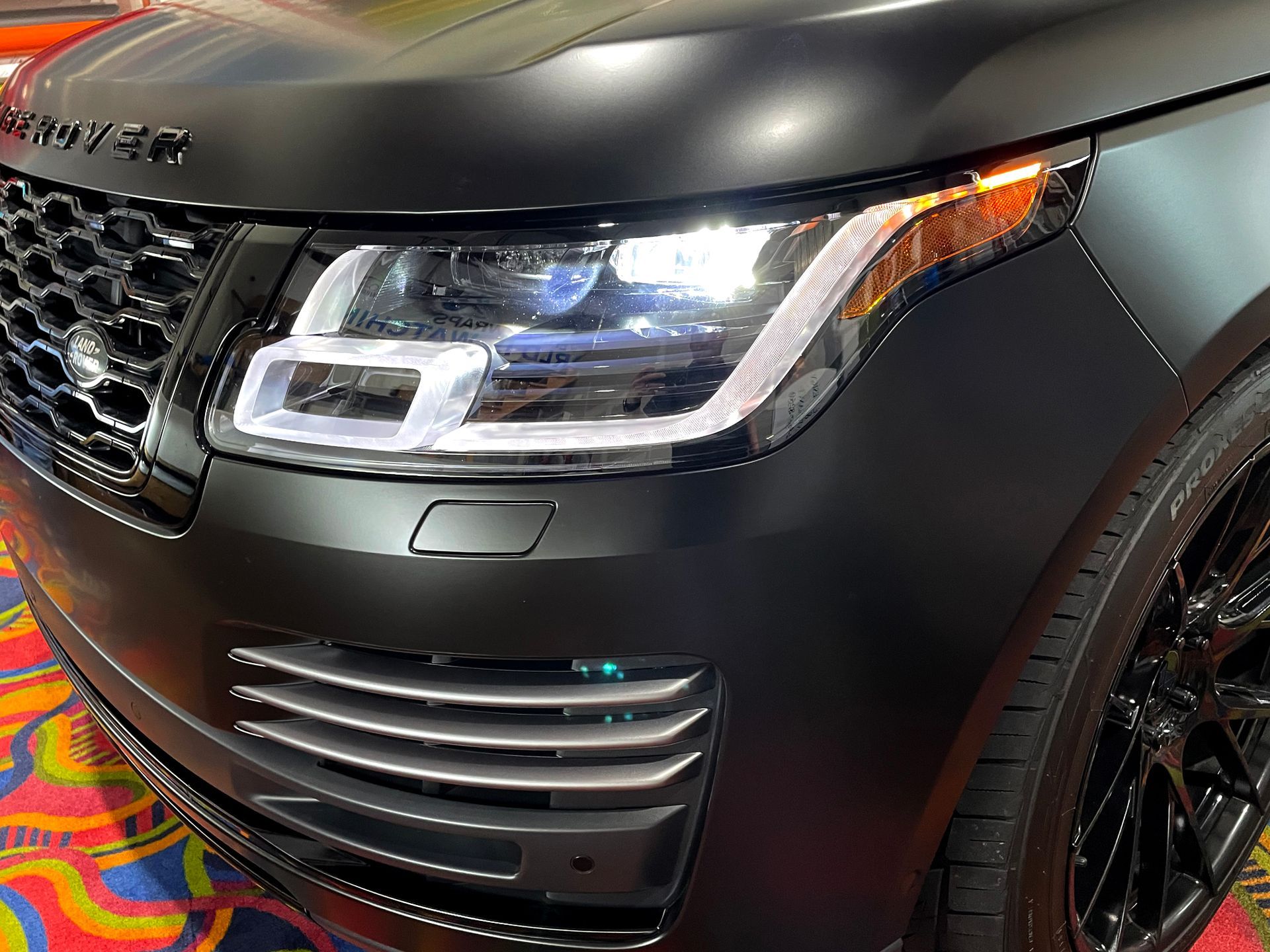 A black range rover is sitting on a colorful carpet.