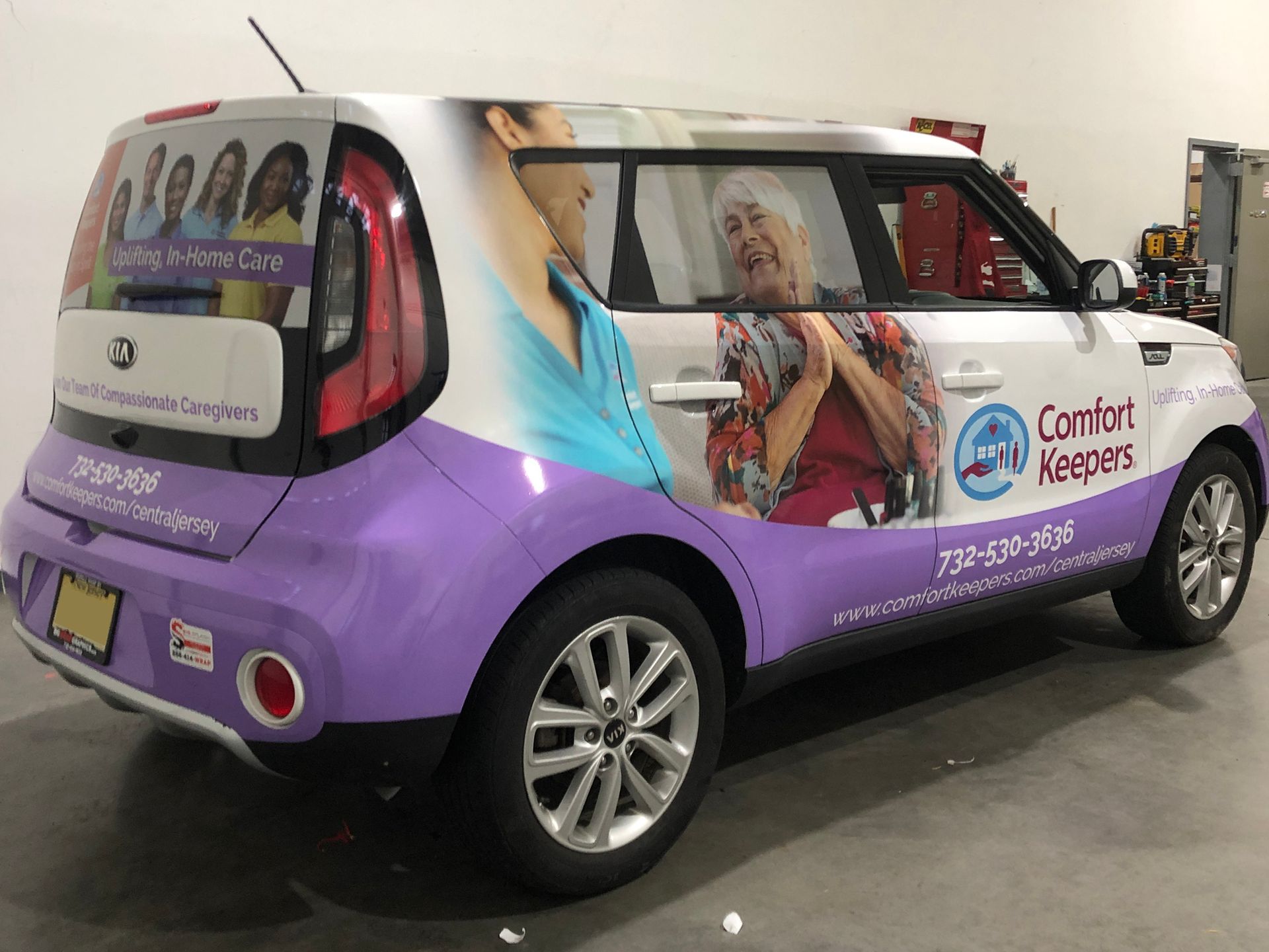 A purple and white car with a picture of an elderly woman on the side.