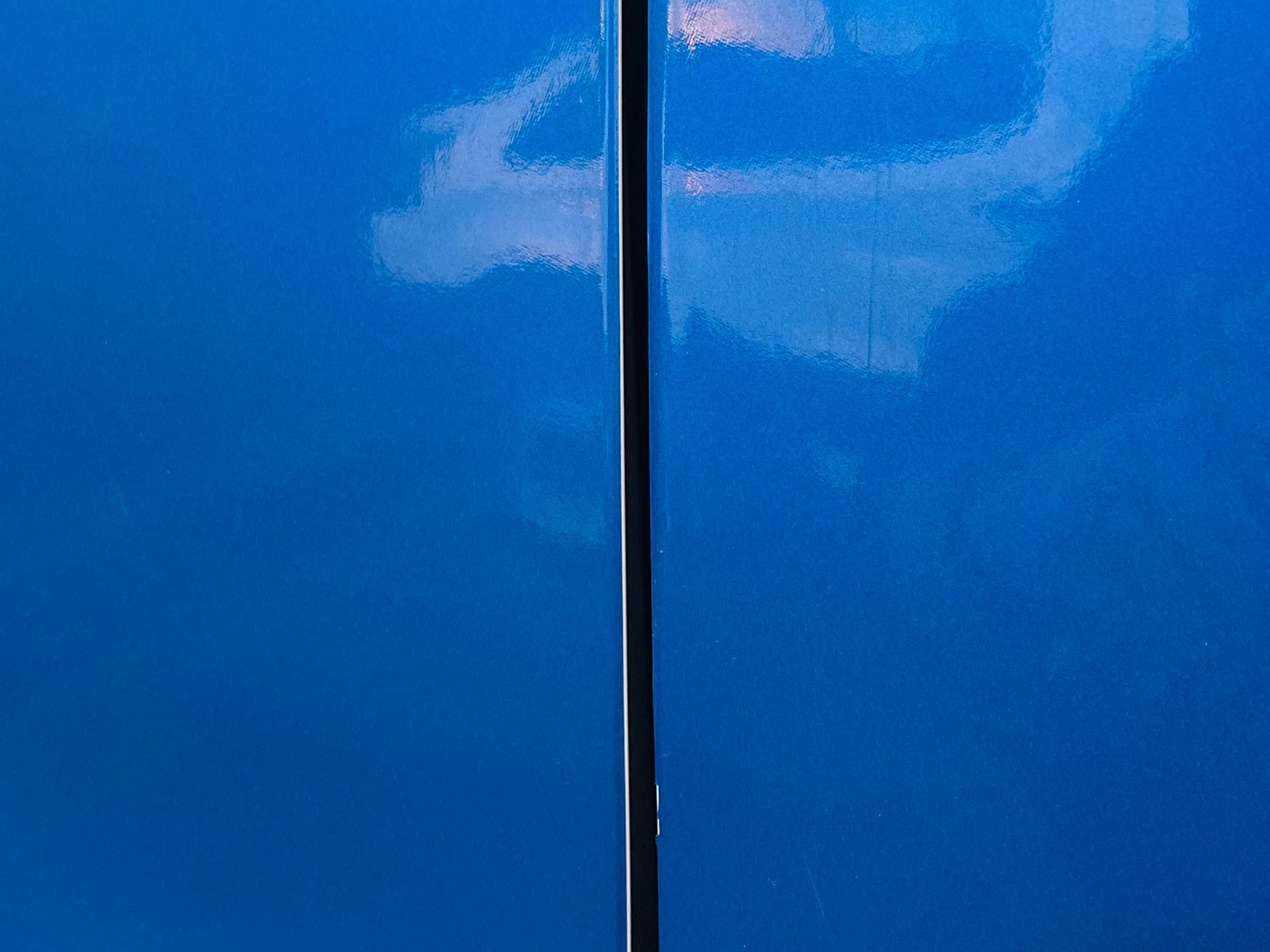 A close up of a blue car door with a pole in the background.