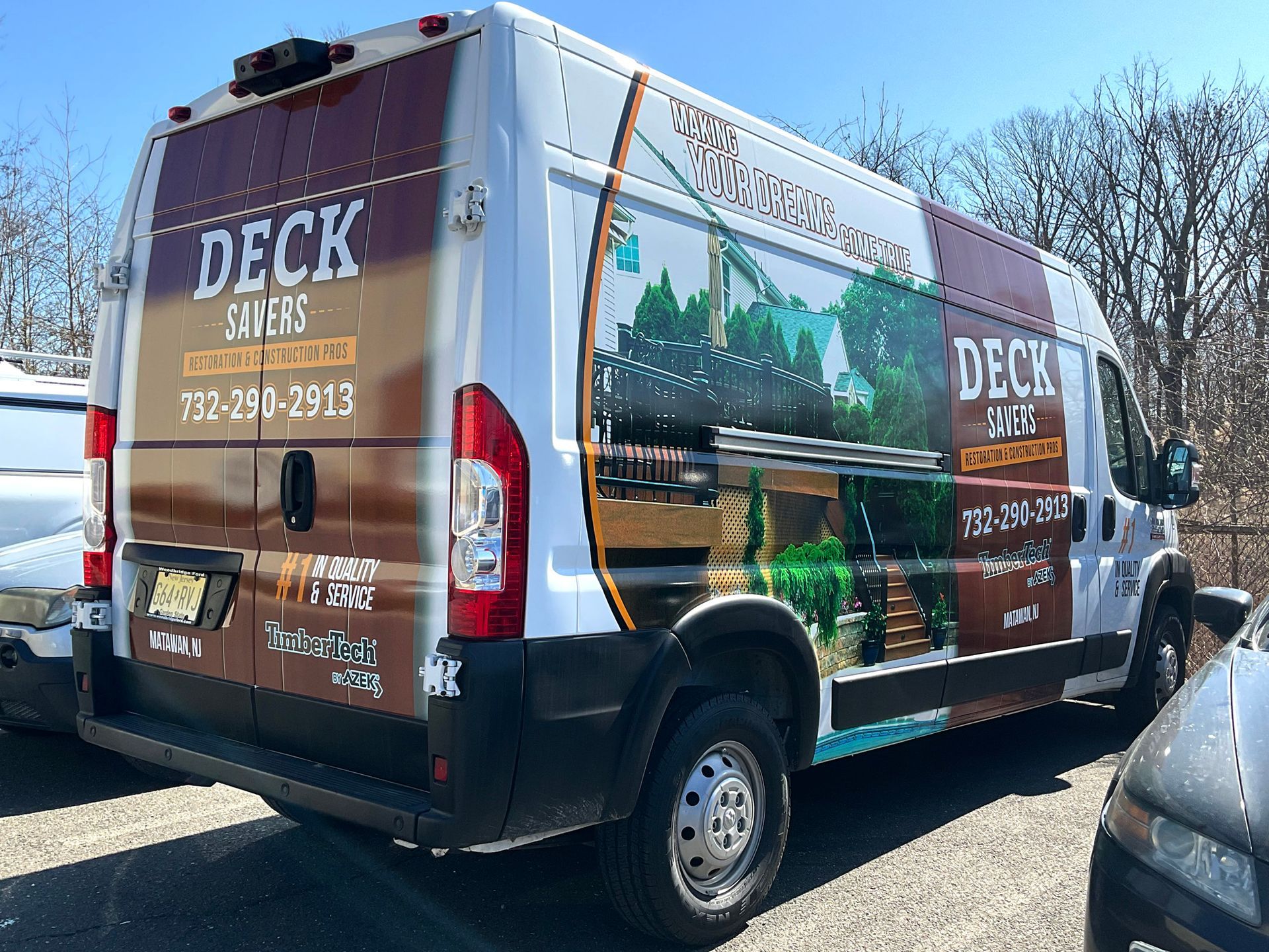 A van with the word deck on it is parked next to a car.