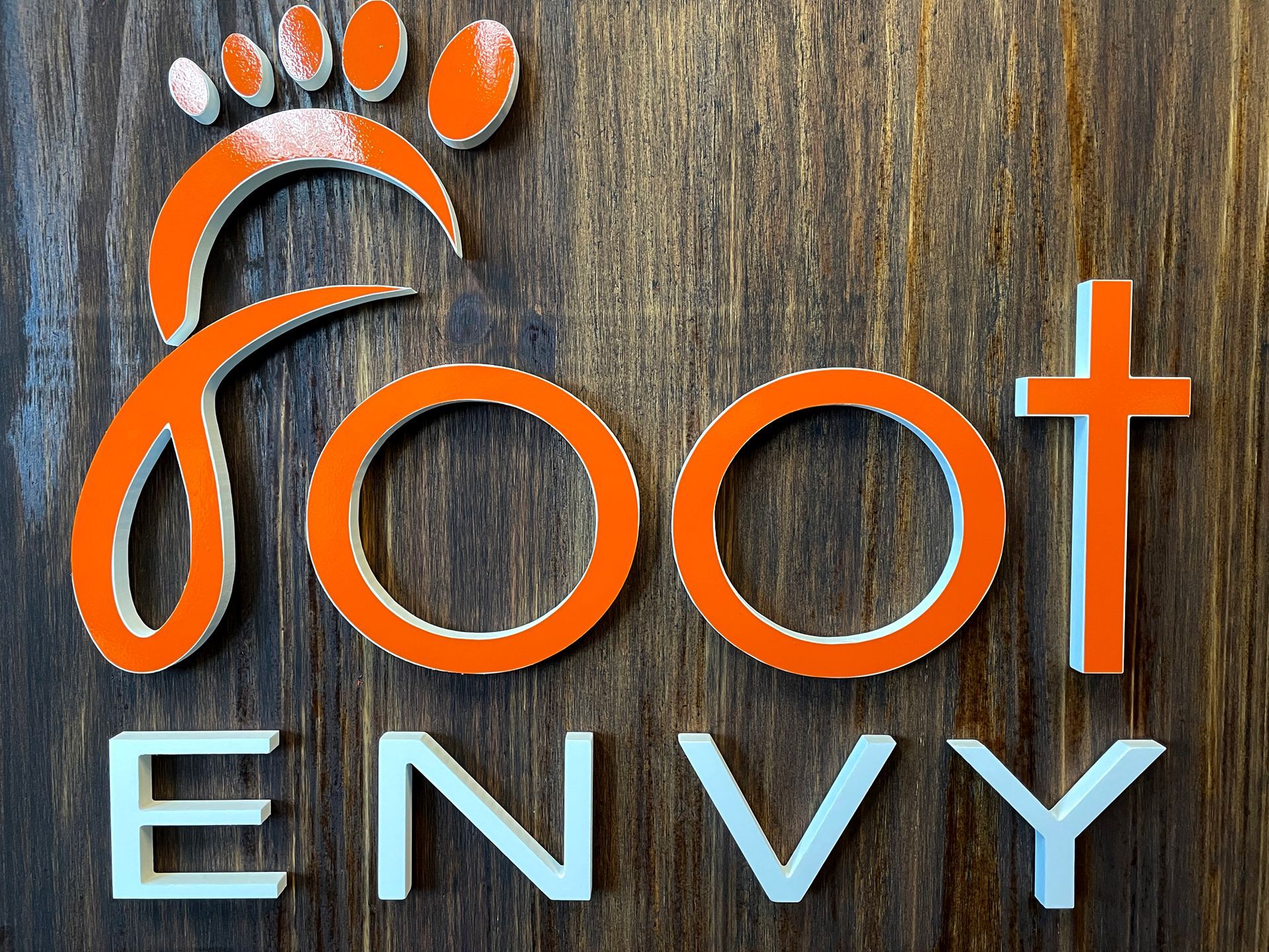 A wooden sign that says foot envy on it