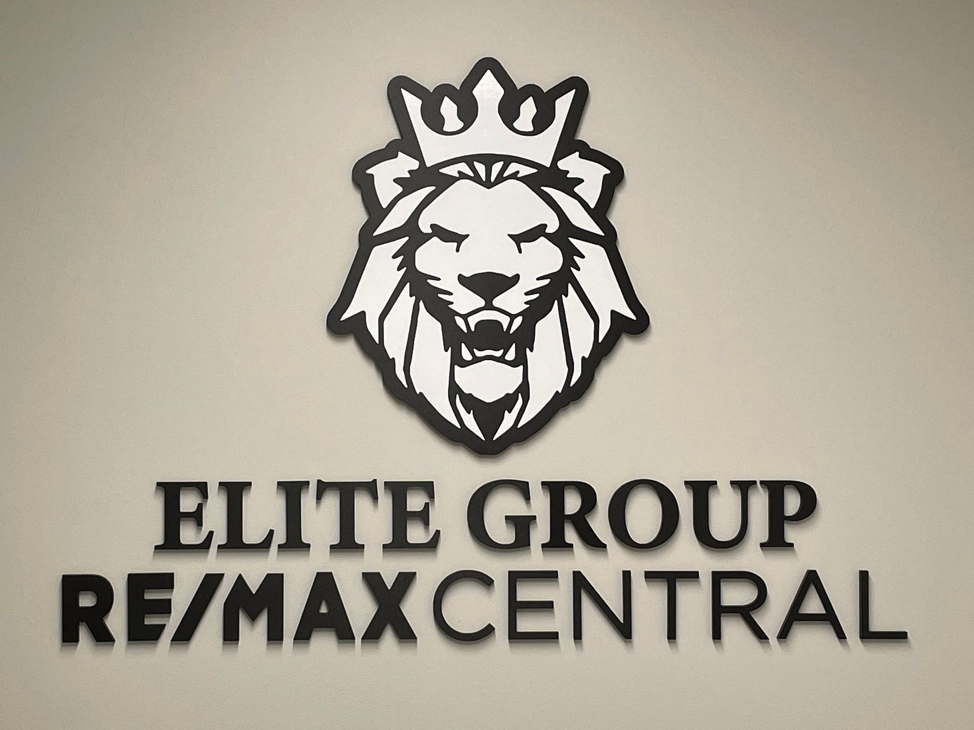 A logo for elite group re / max central with a lion wearing a crown