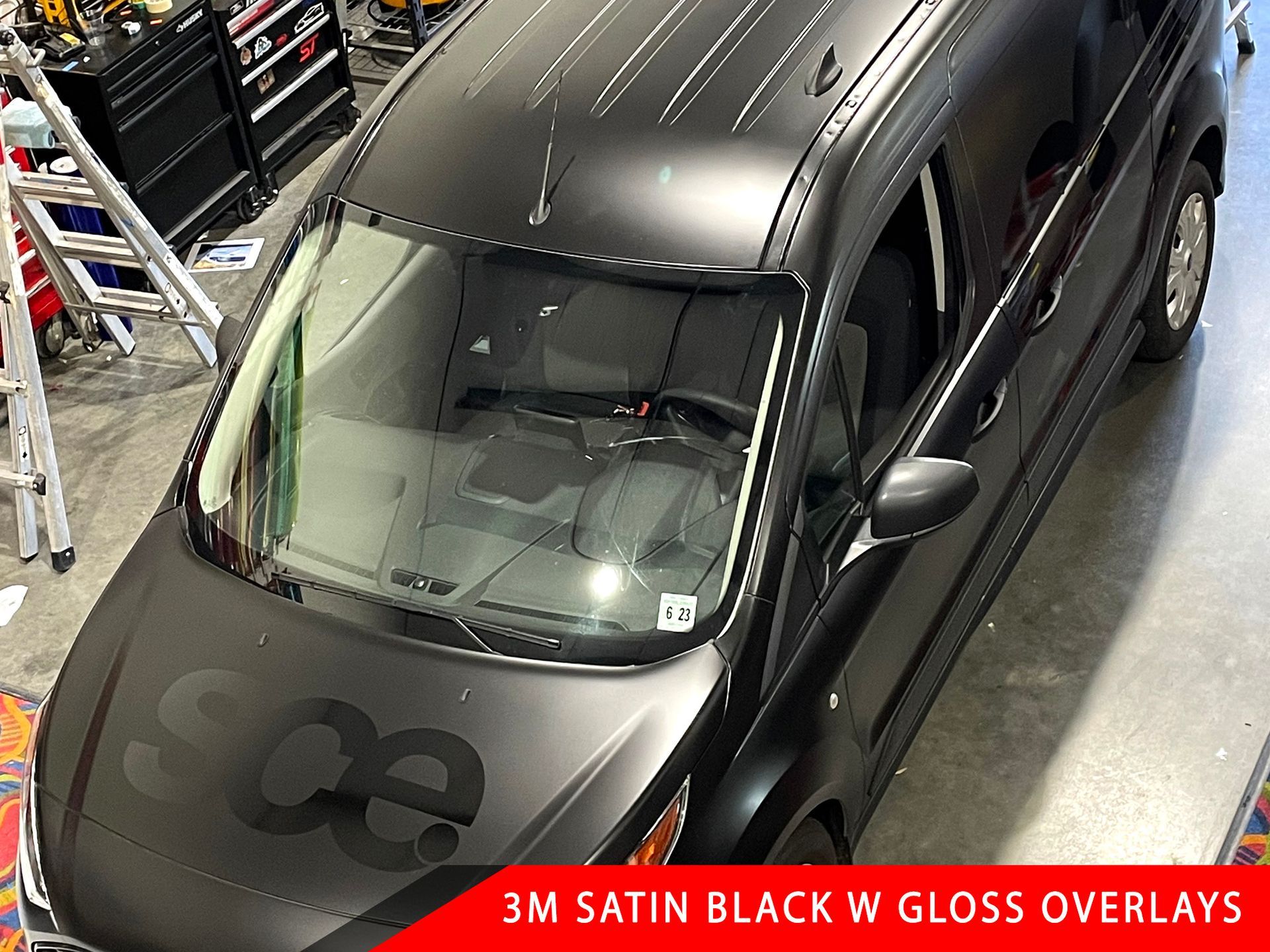 A black van is wrapped in 3m satin black w gloss overlays