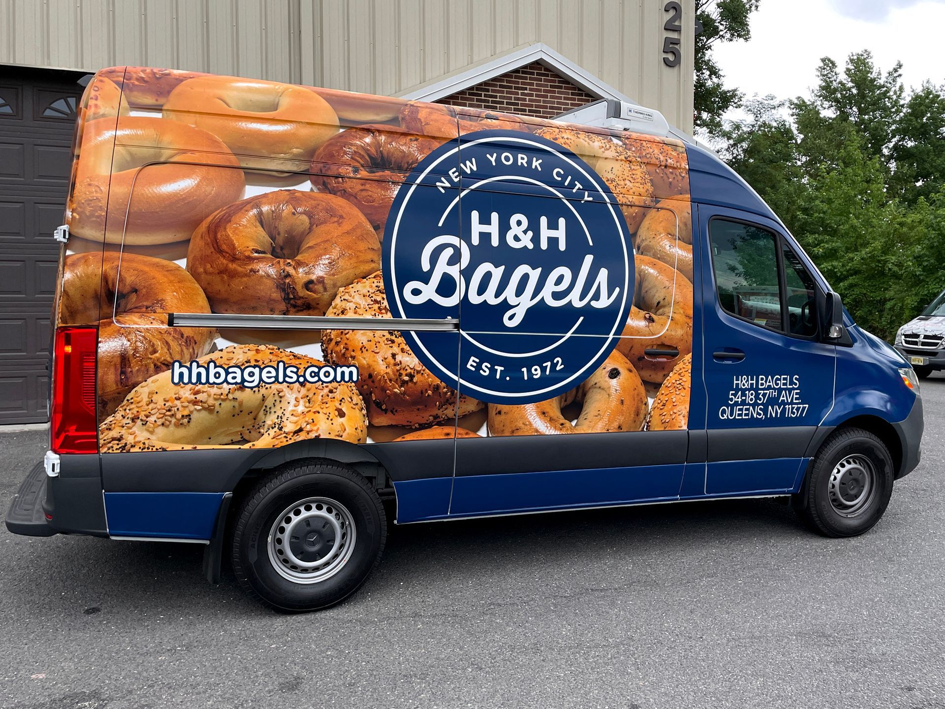 A blue van with a sticker on the side that says h & h bagels