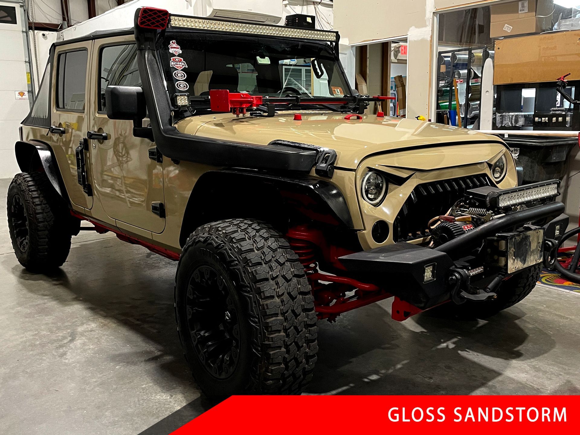 A tan jeep is parked in a garage.