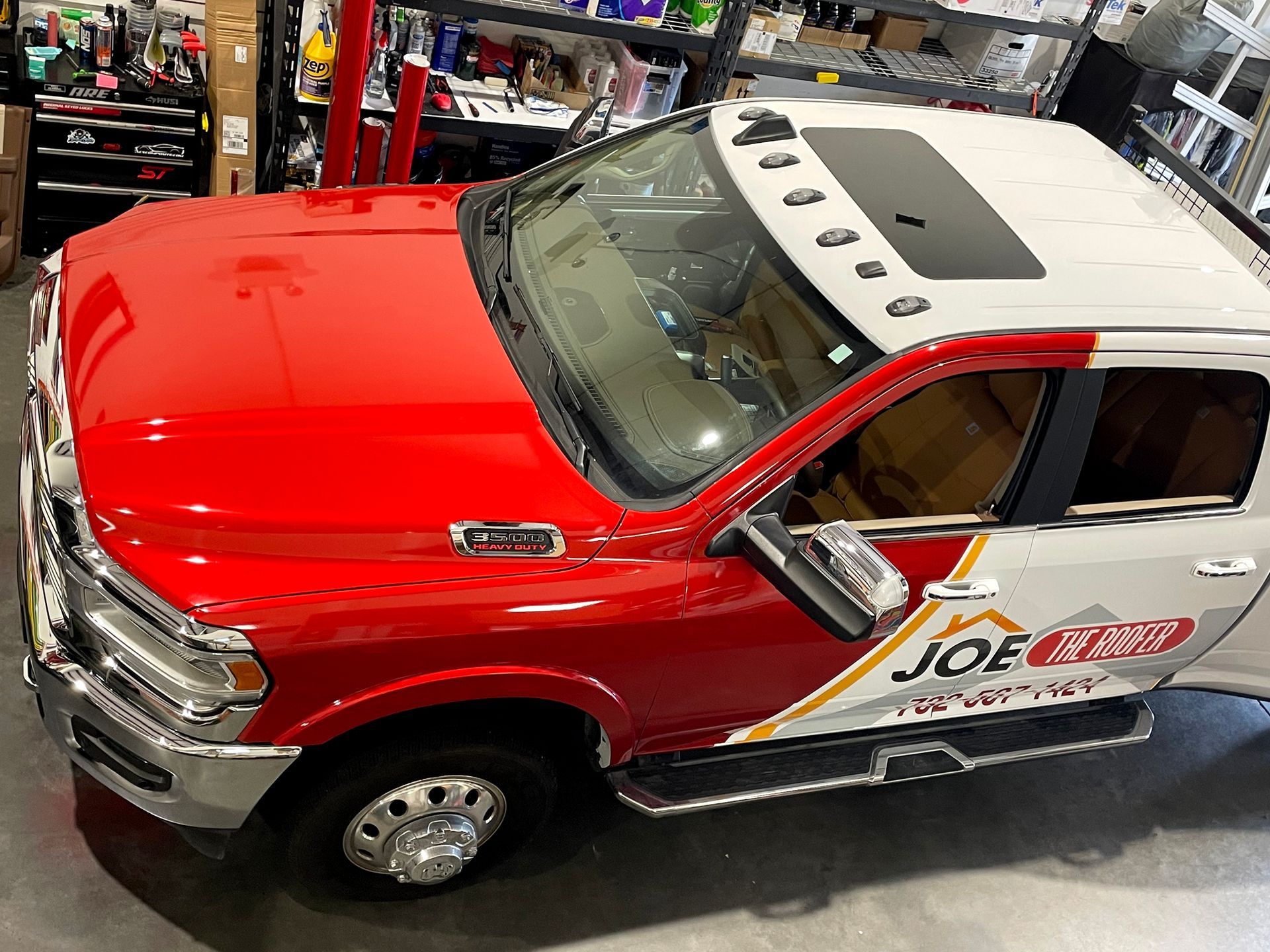 A red and white truck with the word joe on the side is parked in a garage.