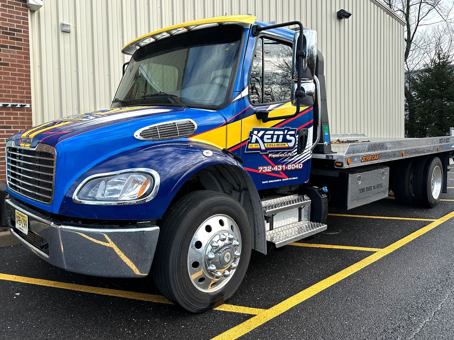 A blue and yellow tow truck is parked in a parking lot.