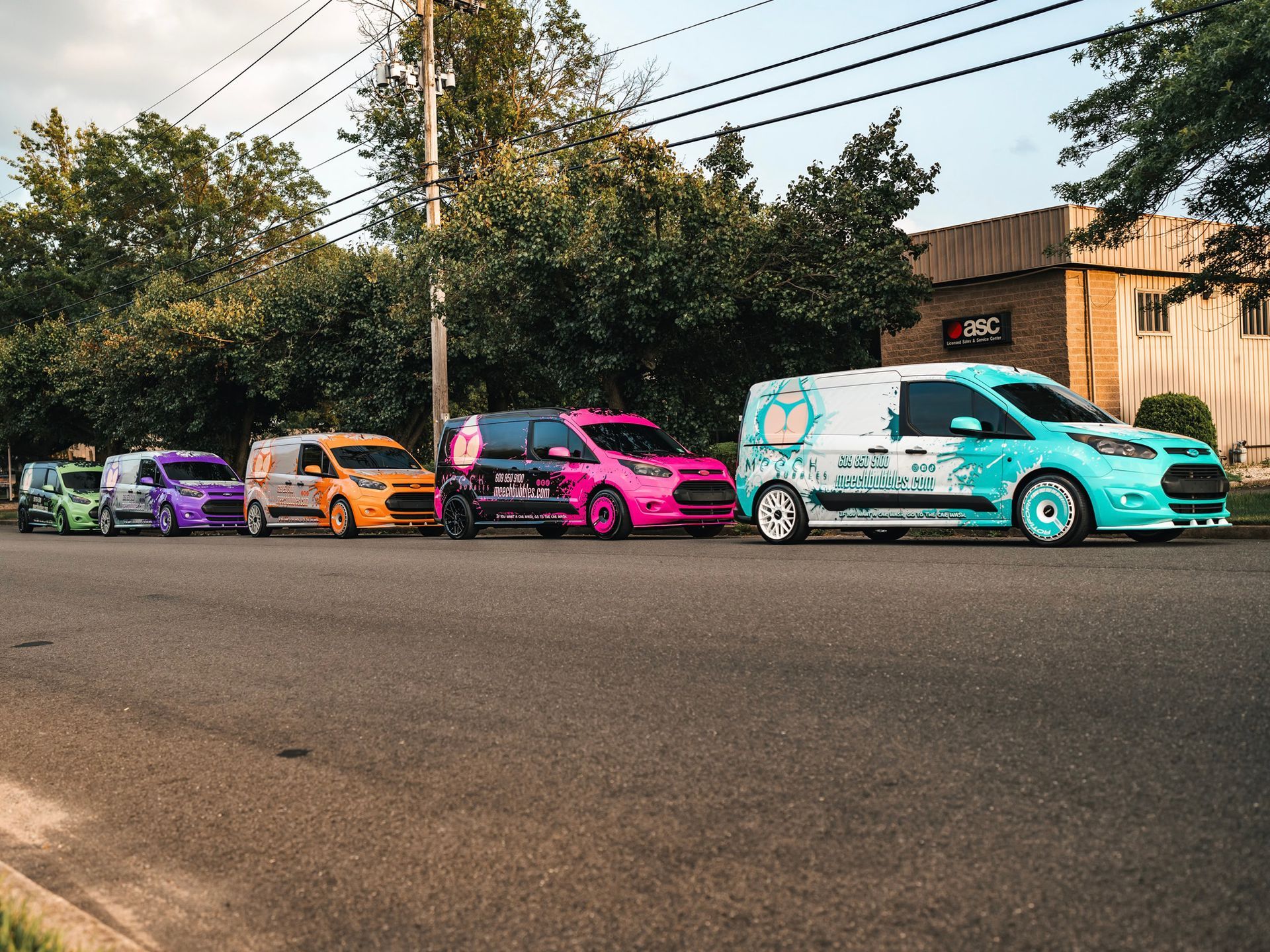 A row of colorful vans are parked on the side of the road.