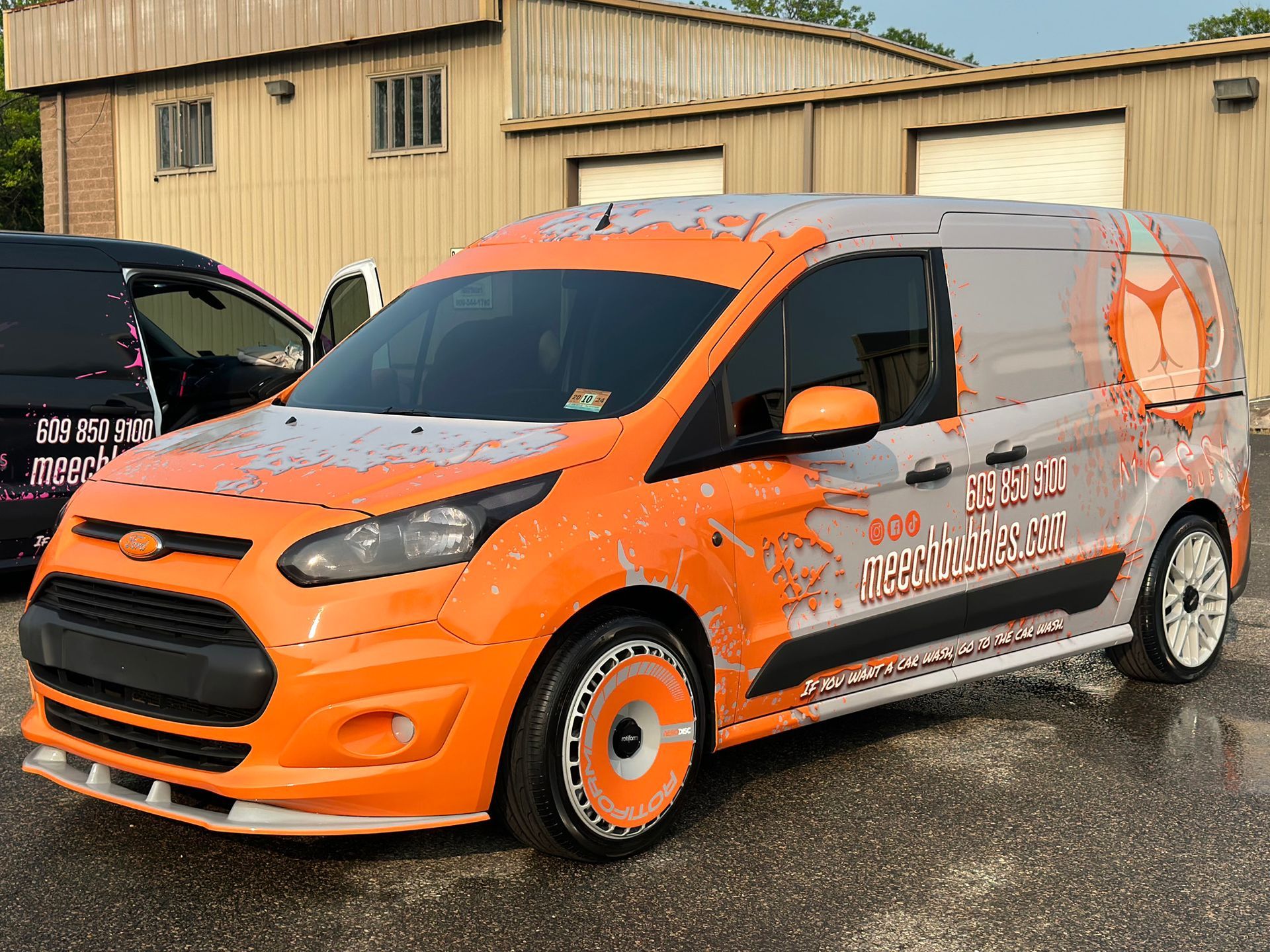 An orange and gray van is parked in front of a building.
