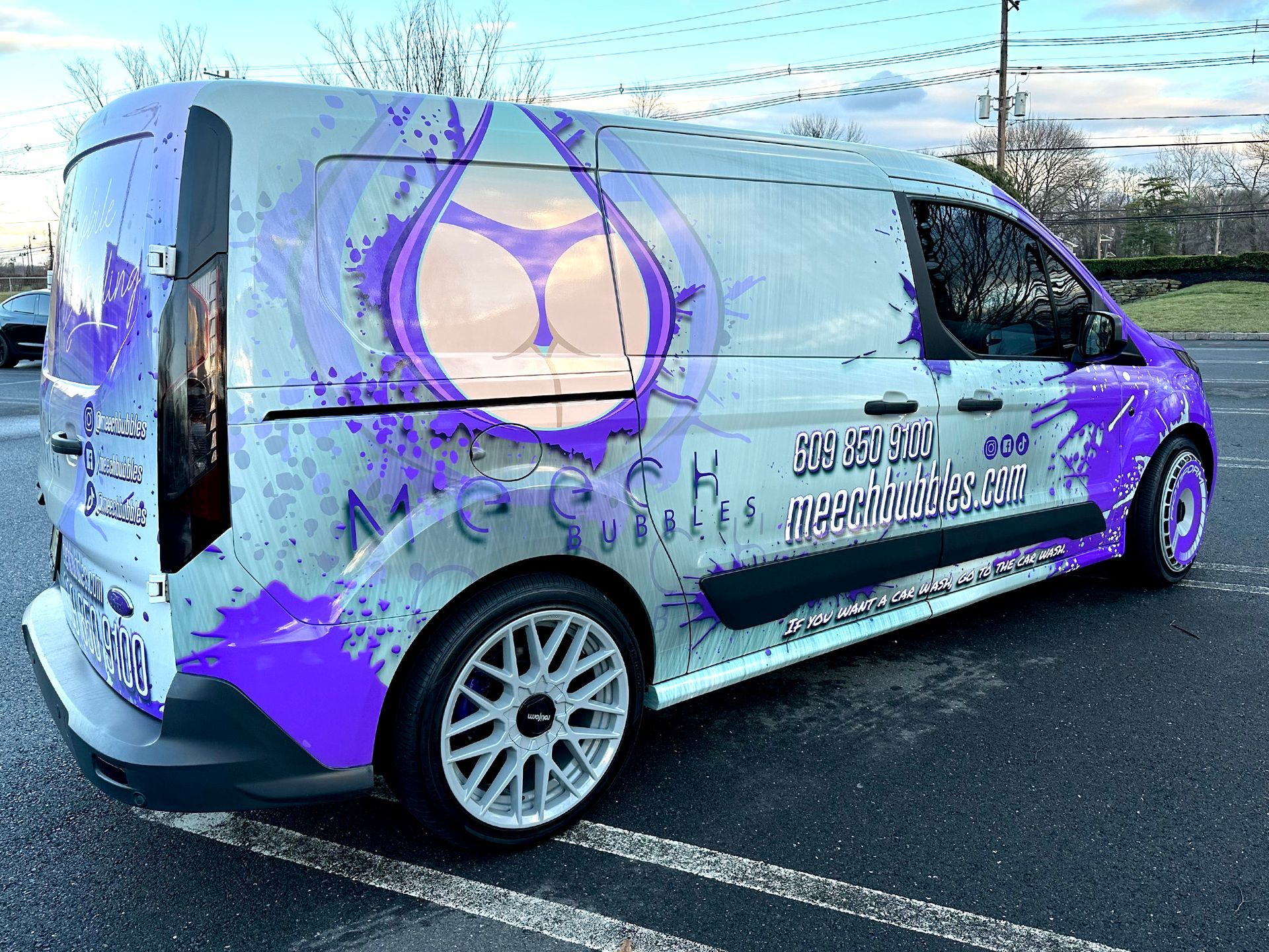 A purple and white van is parked in a parking lot.