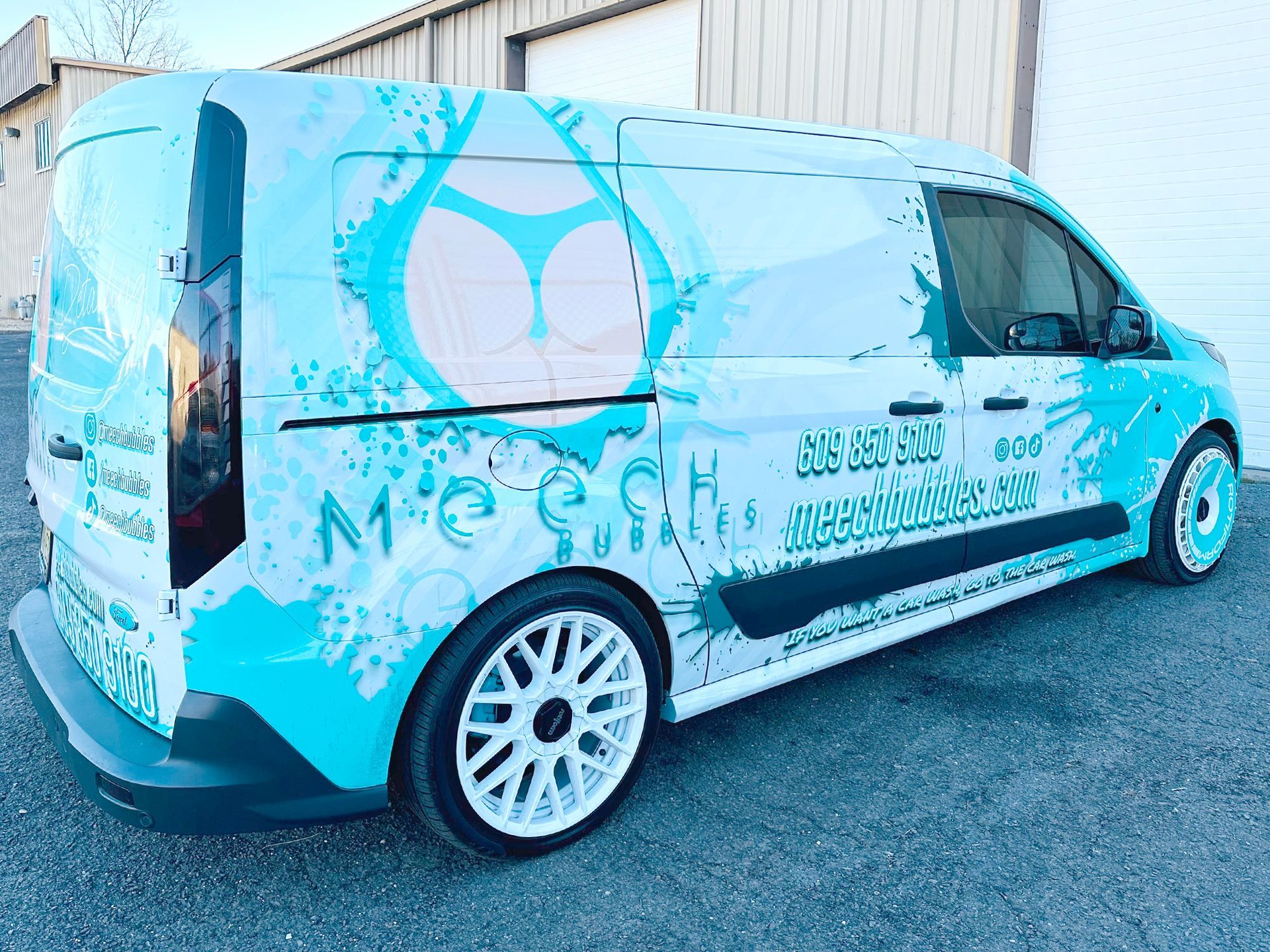 A blue and white van is parked in front of a garage.