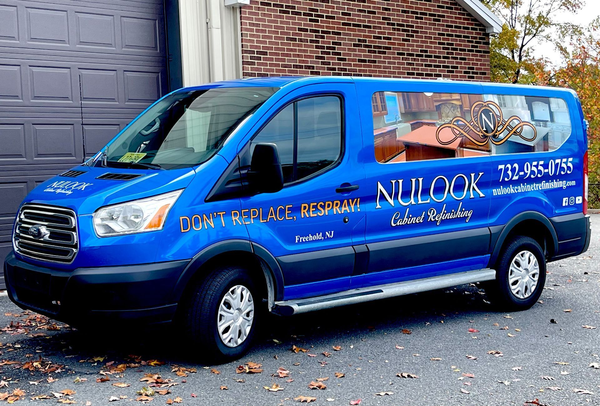 A blue van is parked in front of a garage door.