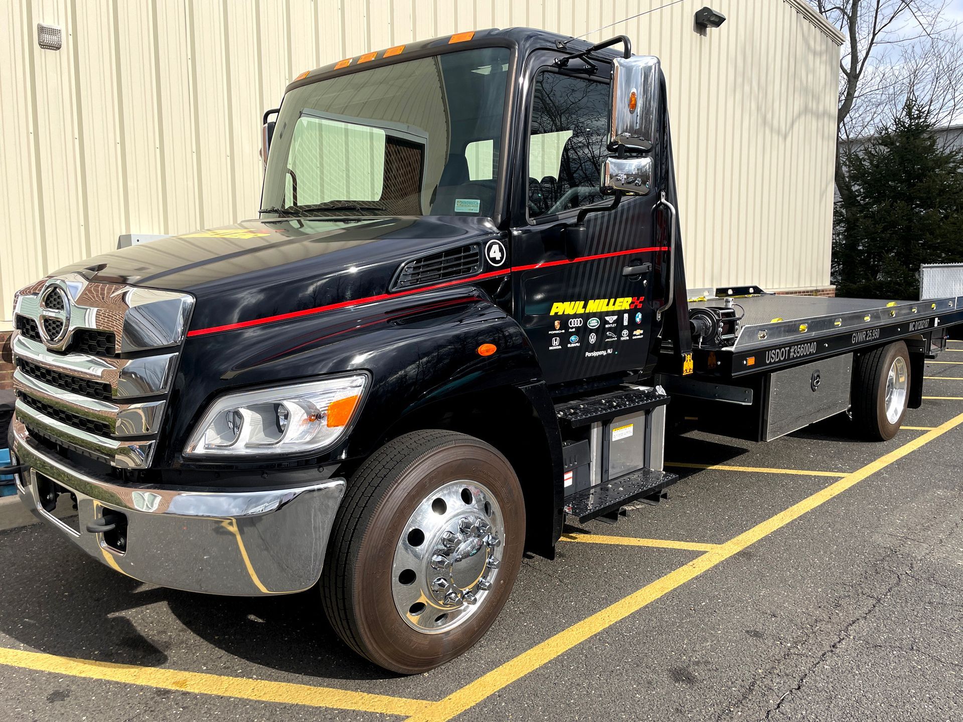 A black tow truck is parked in a parking lot.
