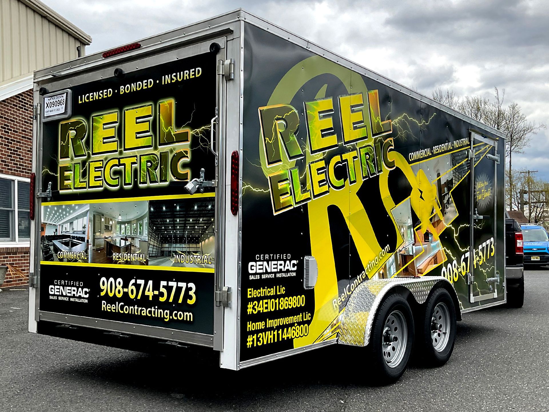 A trailer for reel electric is parked in front of a building.