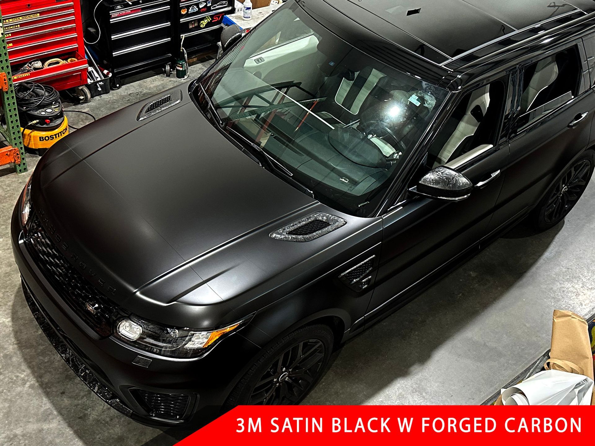 A black range rover is wrapped in 3m satin black w forged carbon