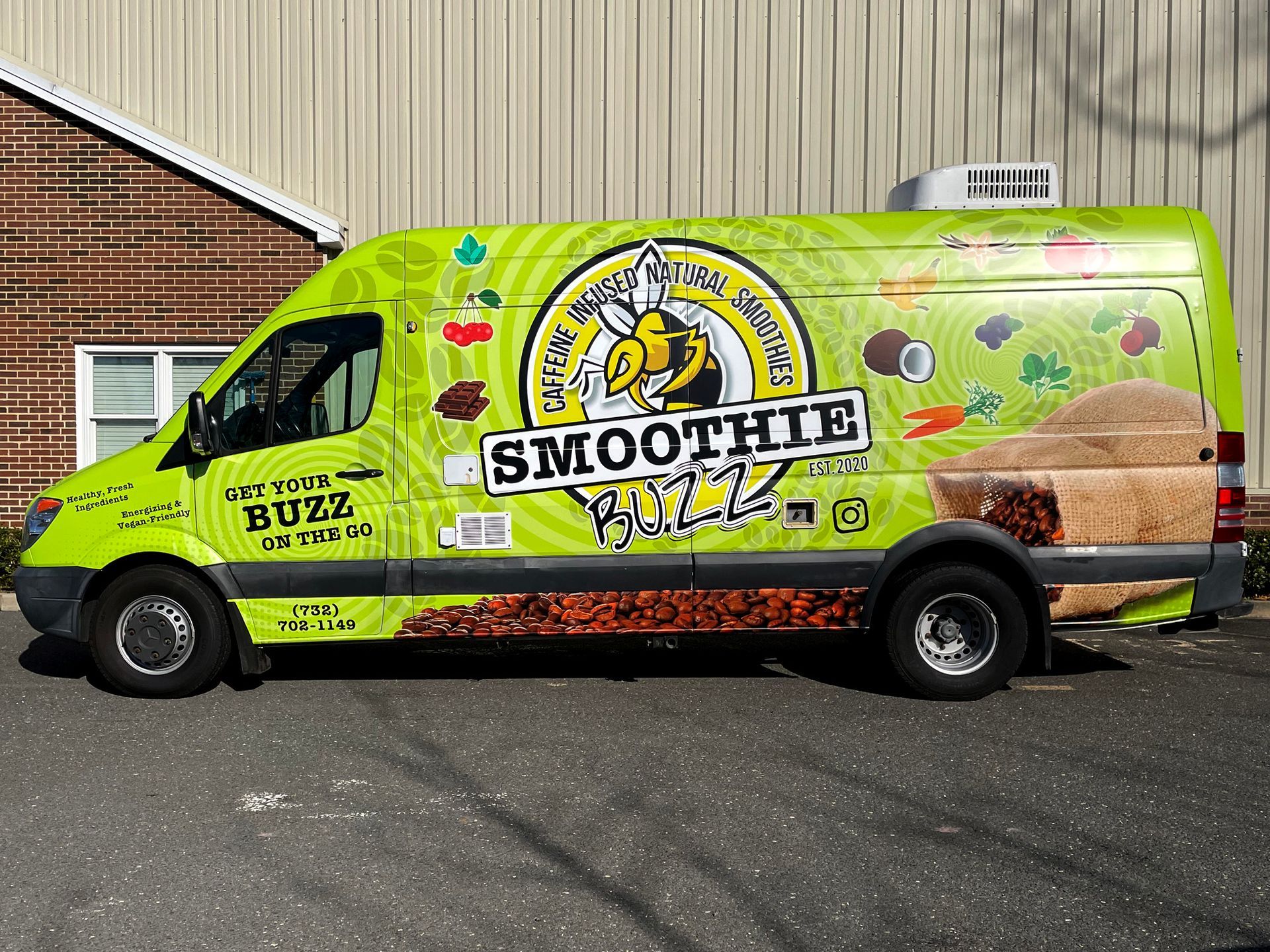 A smoothie buzz van is parked in front of a brick building