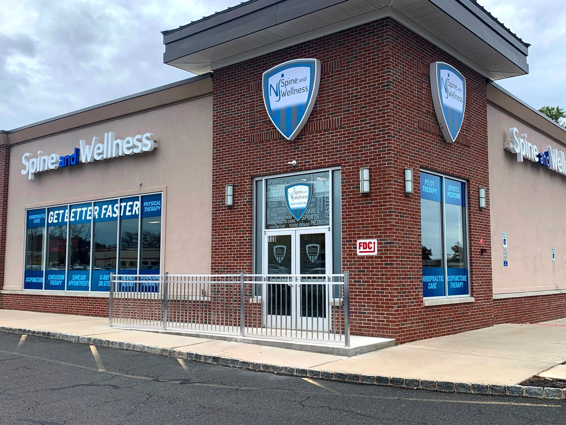 A brick building with a handicap ramp and a sign that says ' spine wellness ' on it.