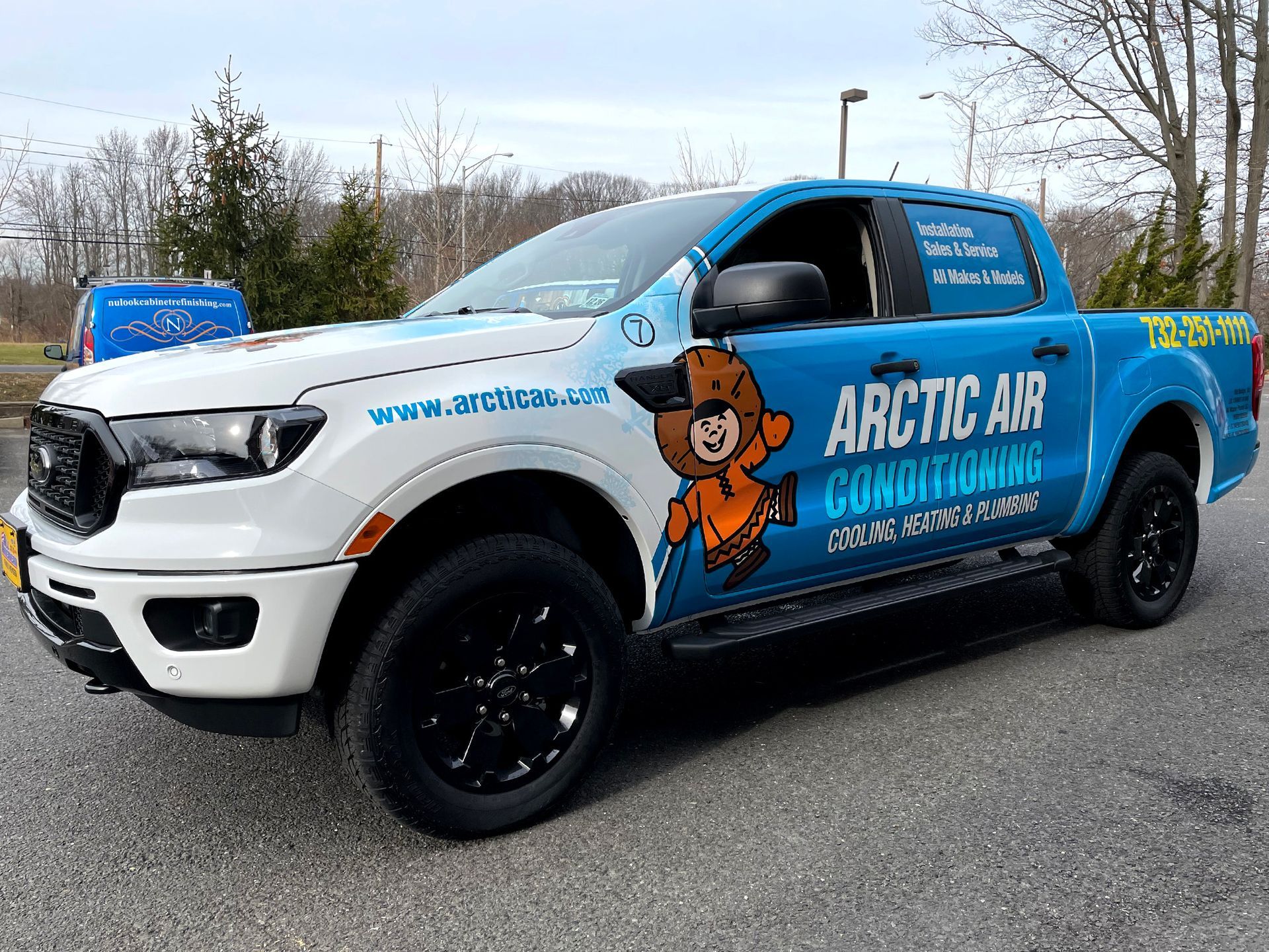 A blue and white truck with a bear on the side is parked on the side of the road.