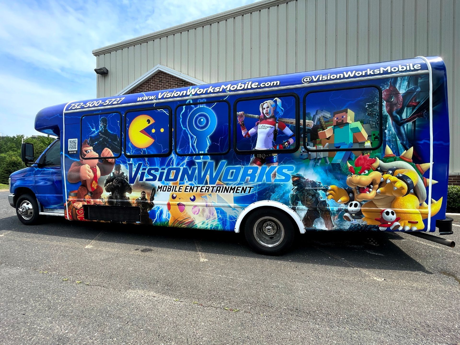 A blue bus with a video game theme is parked in front of a building.