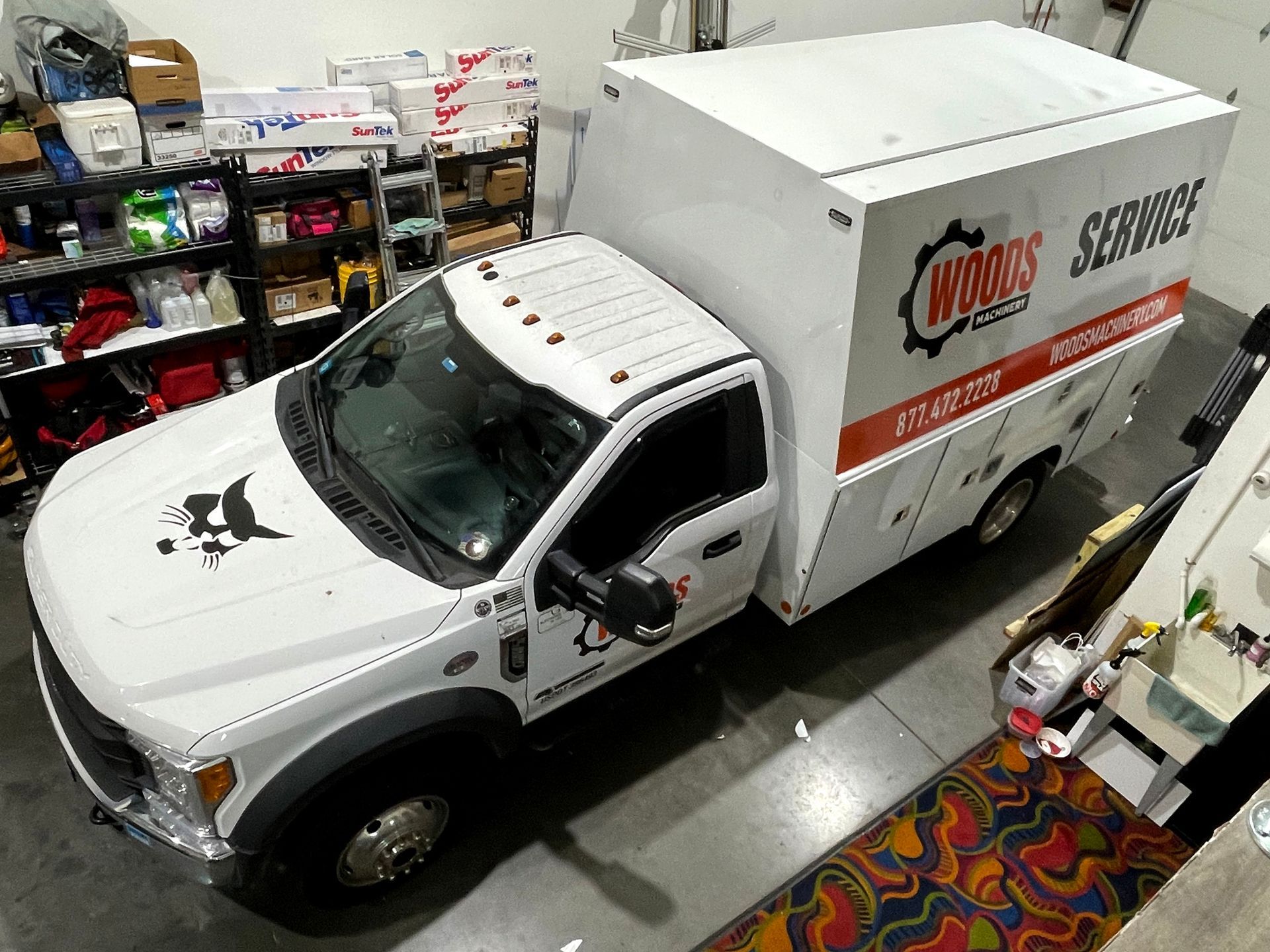 A white truck with a box on the back is parked in a garage.