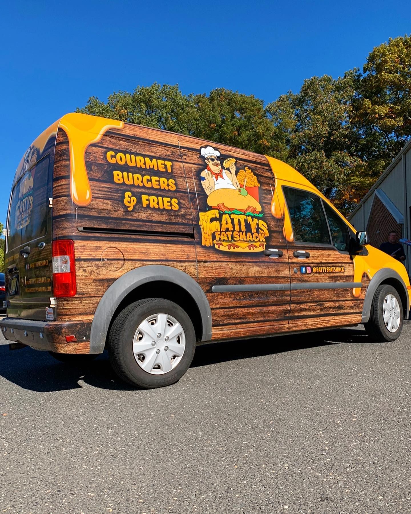 A gourmet burgers and fries van is parked on the side of the road.