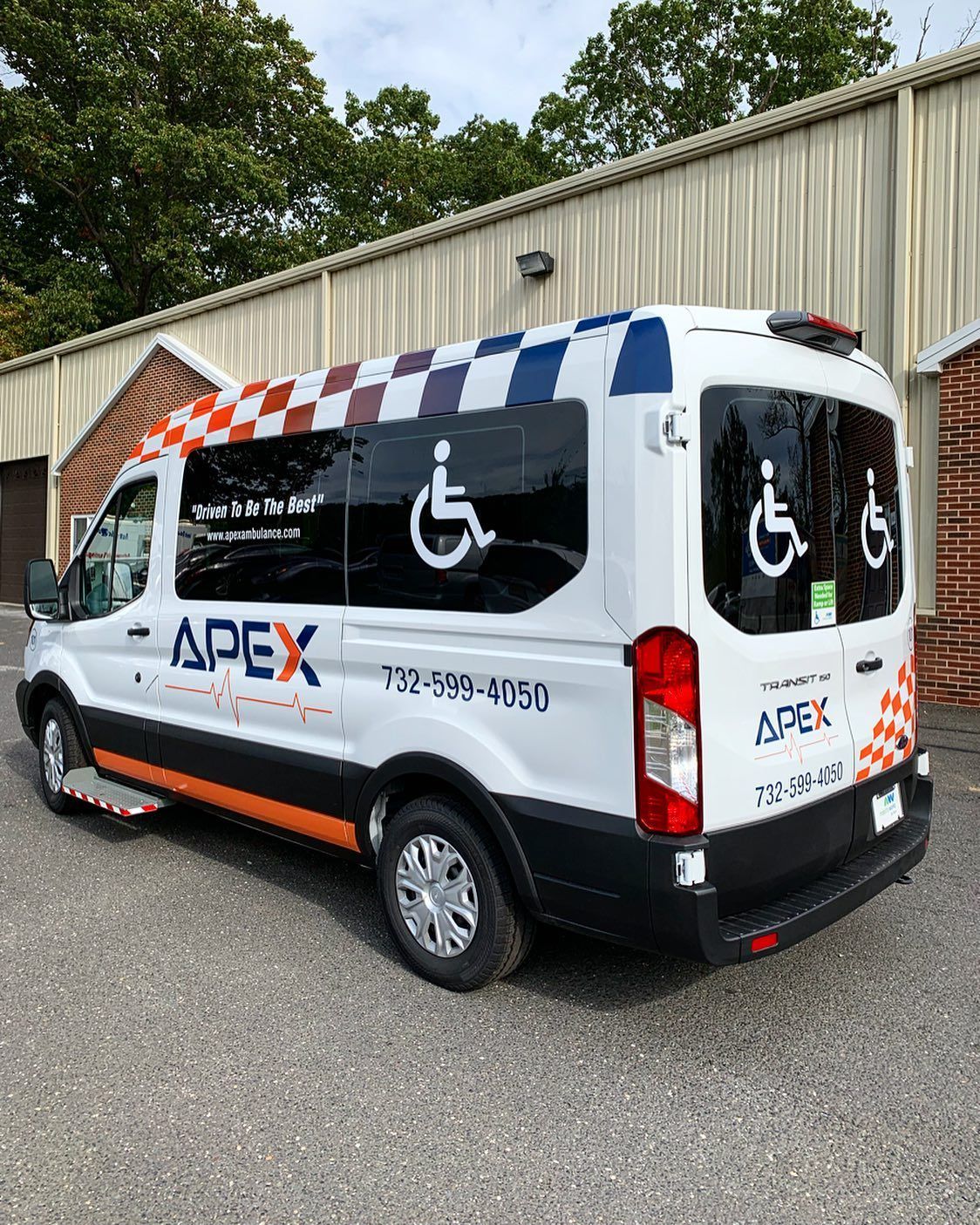 A white van with a handicap sign on the side is parked in front of a building.