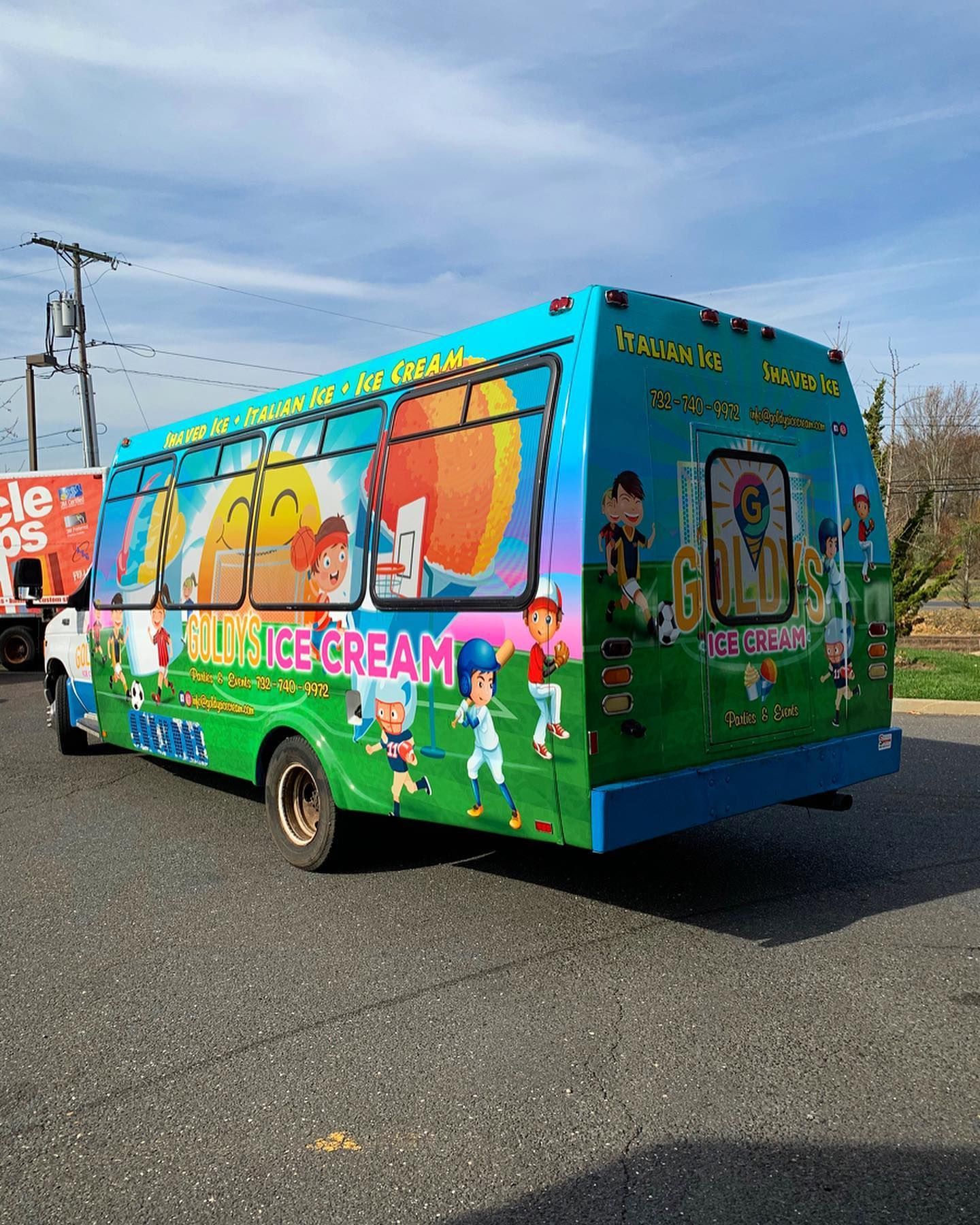 A blue and green ice cream truck is parked on the side of the road.