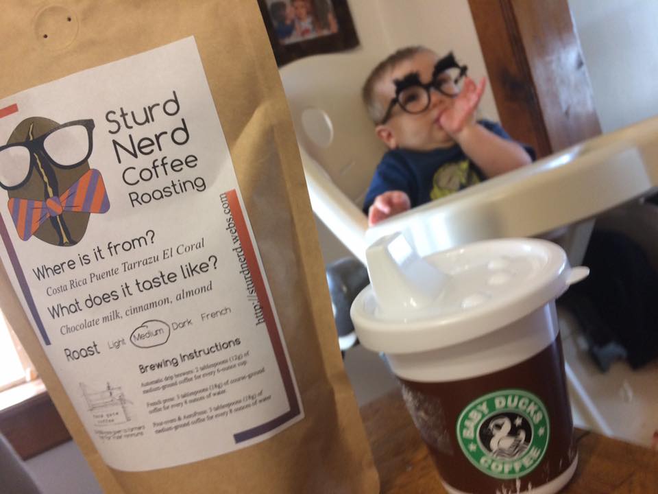 A small child with nerd glasses in the background with a bag of Sturd Nerd coffee in the foreground